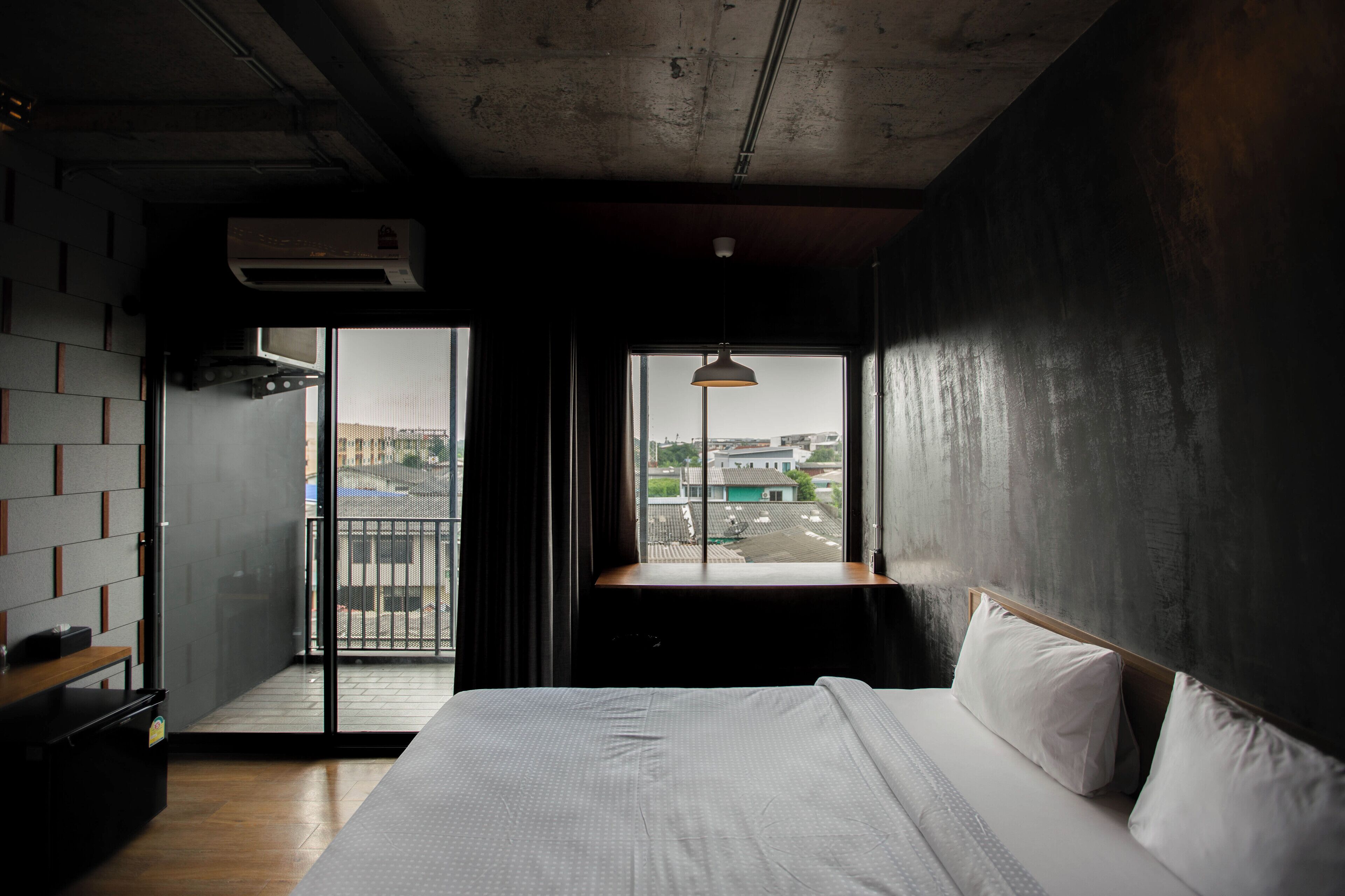 Una habitación de hotel con una cama grande, vistas de la ciudad a través de una ventana y un balcón con vistas panorámicas.