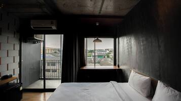 Una habitación de hotel con una cama grande, vistas de la ciudad a través de una ventana y un balcón con vistas panorámicas.