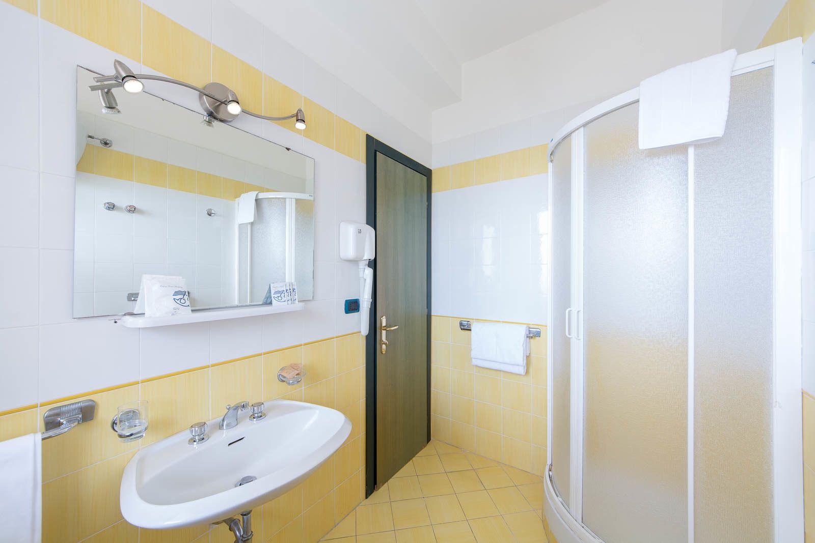 A bathroom with a sink, mirror, shower, and towel rack.
