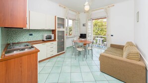 A compact kitchen with a microwave, a stove, and a dining area with a table and chairs. - La Residenza Aparthotel (Maiori)