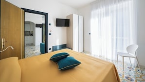 A hotel room with a bed, a TV, a wardrobe, and a view of the kitchen. - La Residenza Aparthotel (Maiori)