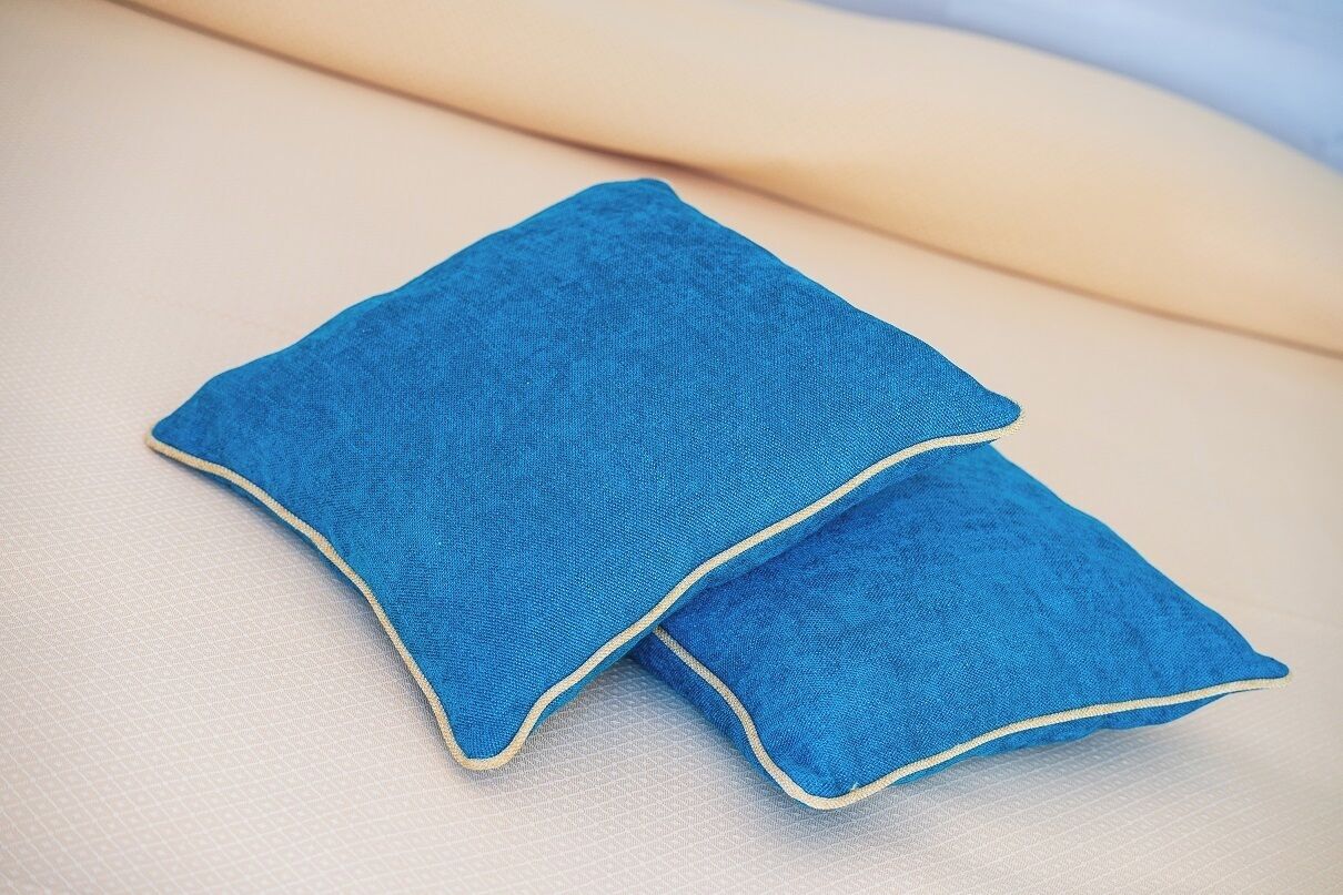 A blue pillow with a yellow border on a textured surface.