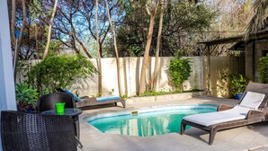 A backyard with a swimming pool, wicker furniture, and potted plants. - Luxury Apartment at Peo (Maun)