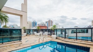 A rooftop pool with clear blue water, surrounded by white lounge chairs and potted plants. - Ad404 Stylish Apartment in the Best Part of Itaim (São Paulo)