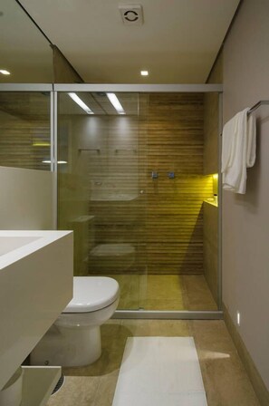 Une salle de bain moderne avec une douche à l’italienne en verre, des toilettes blanches et un lavabo blanc.