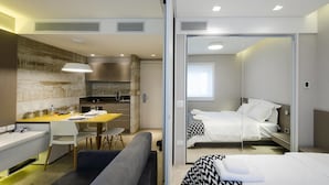 Une chambre d’hôtel moderne dotée d’une kitchenette, d’un coin repas et d’une chambre à coucher séparée.