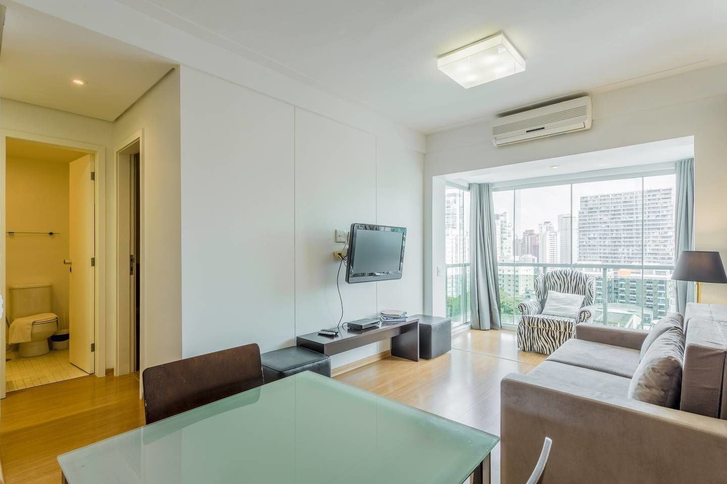 A modern living room with a flat-screen TV, a dining table, and a sofa.