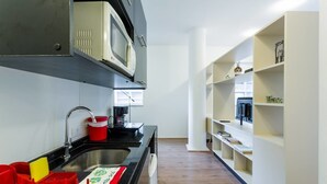 A compact kitchen with a microwave, sink, and modern shelving.