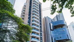 Un hôtel moderne avec une entrée incurvée, un fourgon garé devant, et un grand immeuble avec des balcons en arrière-plan.