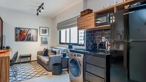 A modern kitchen with a washing machine, a coffee machine, and a refrigerator. - Ad604 Estúdio a 1 Quadra da Av. Paulista (São Paulo)