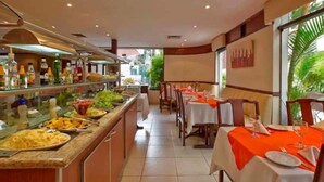 A buffet area with various food items and a dining section with tables set for guests.