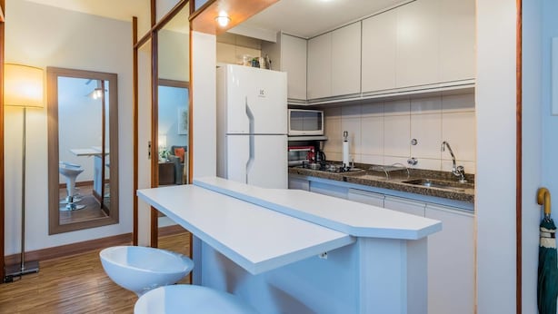 A compact kitchen with white cabinets, a microwave, a sink, and a countertop.
