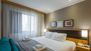A hotel room with a large bed, two pillows, a bedside table with a phone and a remote, a chair, and a window with sheer curtains. - Ce806 Flat Para 1 ou 2 Pessoas nos Jardins! (São Paulo)