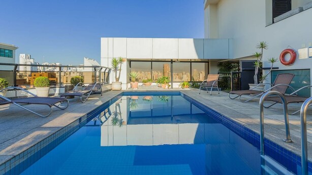 A rooftop pool with lounge chairs, potted plants, and a city view. - Ce806 Flat Para 1 ou 2 Pessoas nos Jardins! (São Paulo)