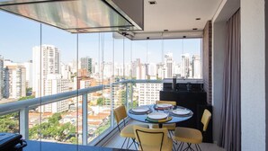 Un balcón con una mesa lista para comer, con vistas a un paisaje urbano de edificios altos.