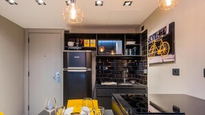 A modern kitchen with a built-in refrigerator, a stove, and a dining area with a table set for two. - Hb1911 Charme e Estilo no Melhor no Jardins! (São Paulo)