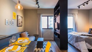 A modern hotel room with a dining area, a sofa, a bed, and a bookshelf. - Hb1911 Charme e Estilo no Melhor no Jardins! (São Paulo)