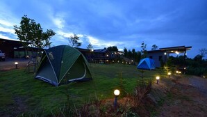 Um camping com tendas e um edifício ao fundo.