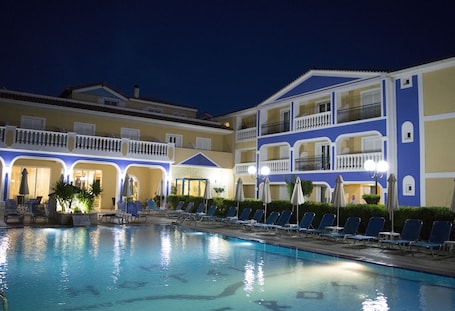 Una piscina al aire libre, sombrillas, sillones reclinables de piscina