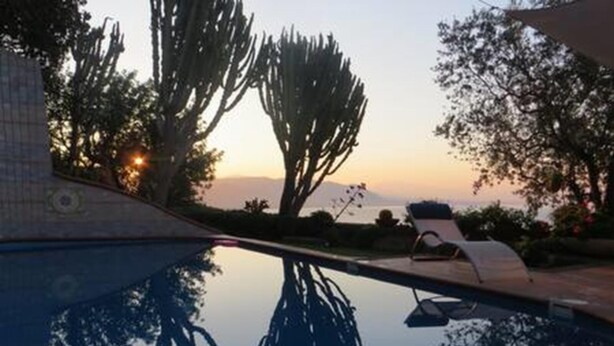 Une piscine avec des chaises longues et une vue sur le coucher de soleil.
