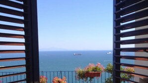 Un balcon avec vue sur la mer, agrémenté d’une balustrade et de plantes en pot.