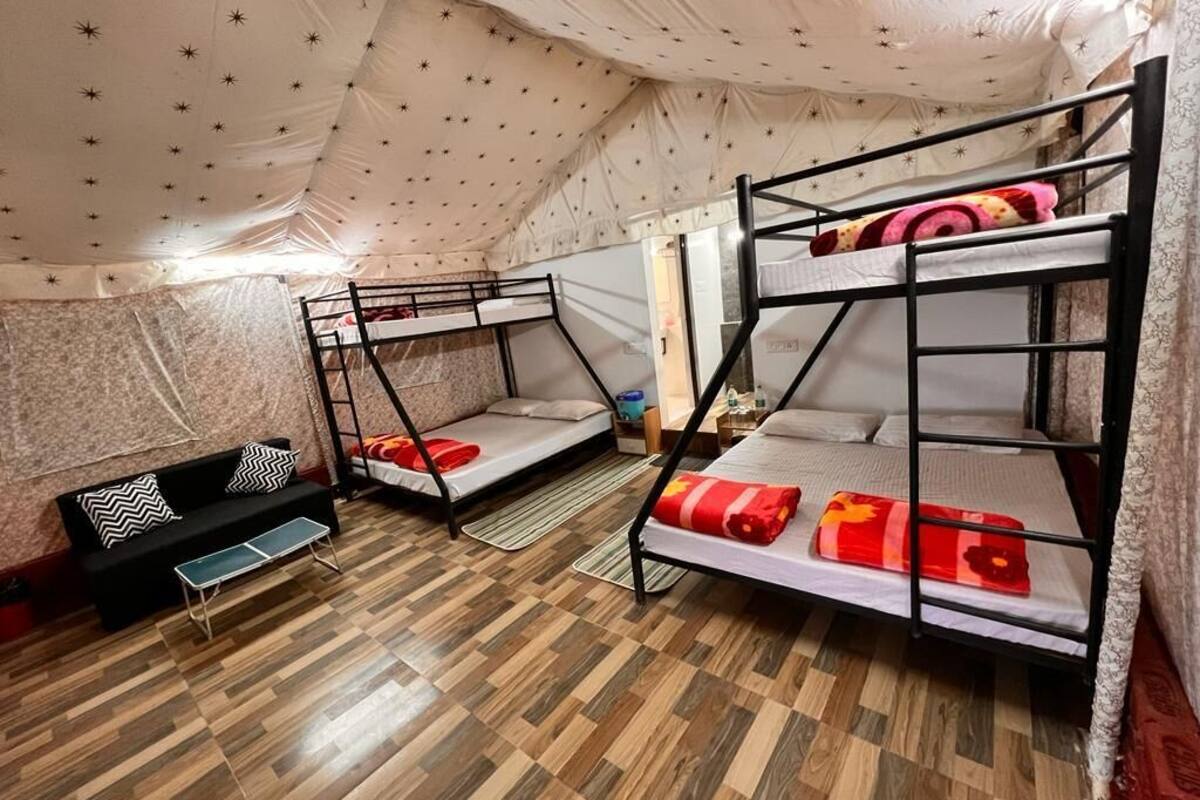 A room with bunk beds, a sofa, and a small table.
