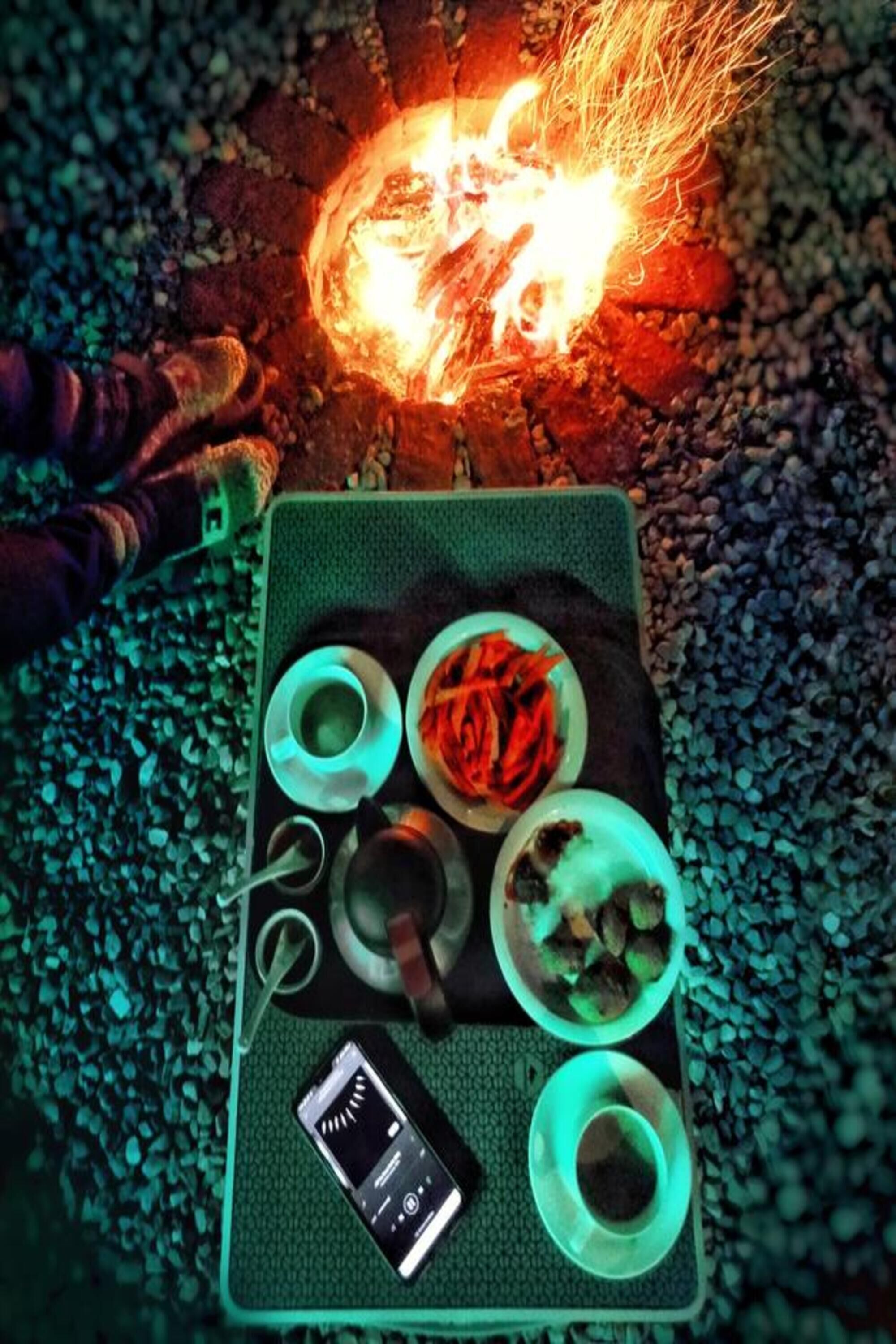 Ein Tisch mit Feuerstelle, Smartphone und Speisen.