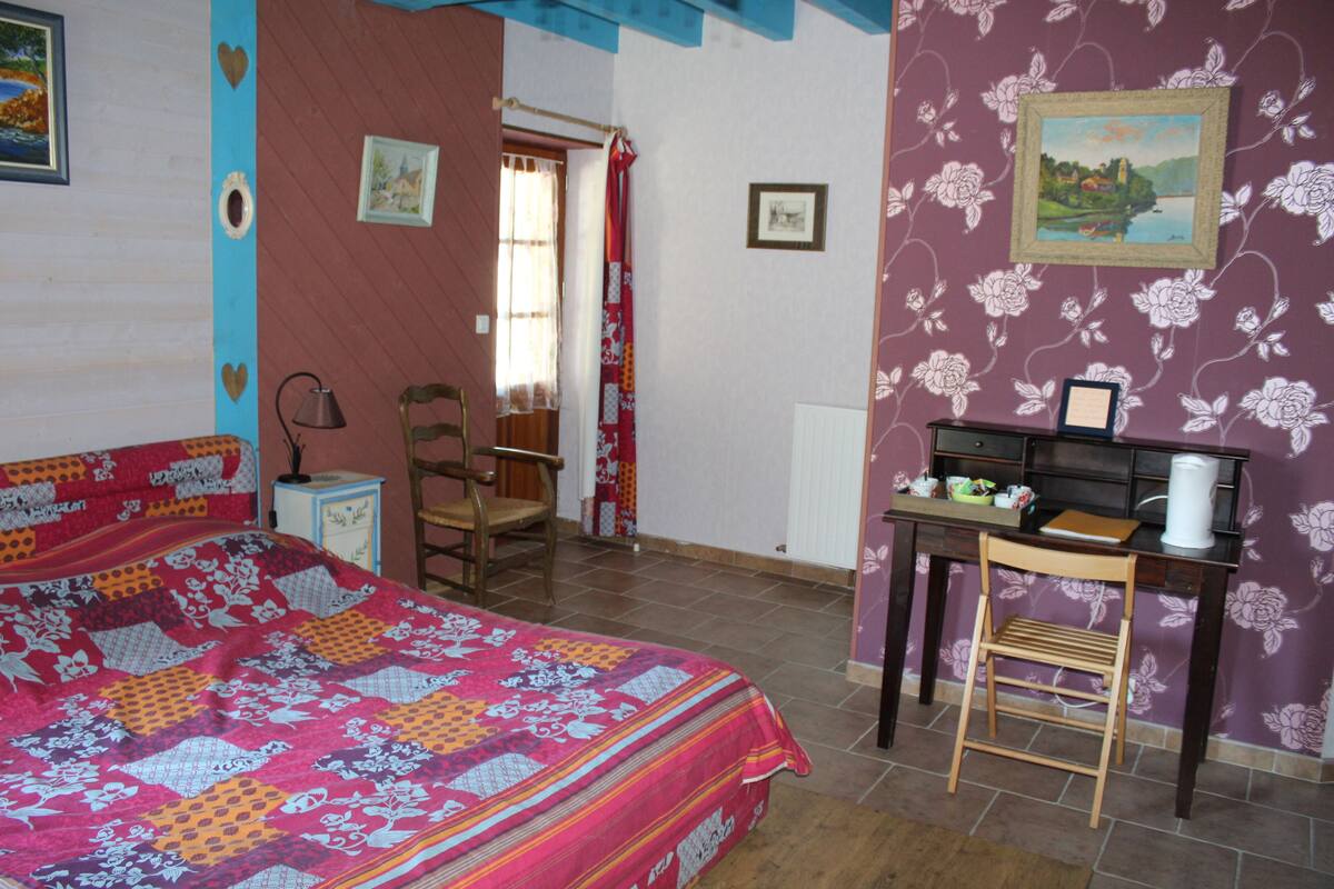 Un dormitorio con cama, escritorio, silla y ventana.