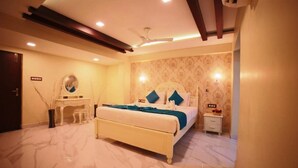 Quarto de hotel com cama, mesa de cabeceira e escrivaninha com cadeira.