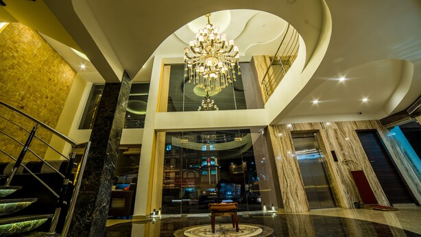 Um hall amplo com um lustre imponente, piso de mármore e escadaria moderna.