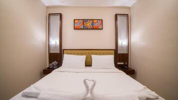 Habitación de hotel con cama, dos mesitas de noche, cabecero y una obra de arte colgada en la pared.