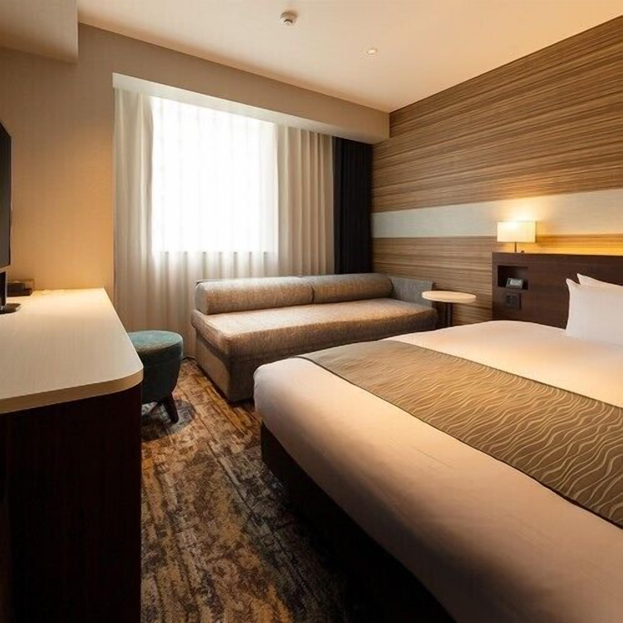 Una habitación de hotel con una cama grande, un sofá, una mesita y un escritorio.