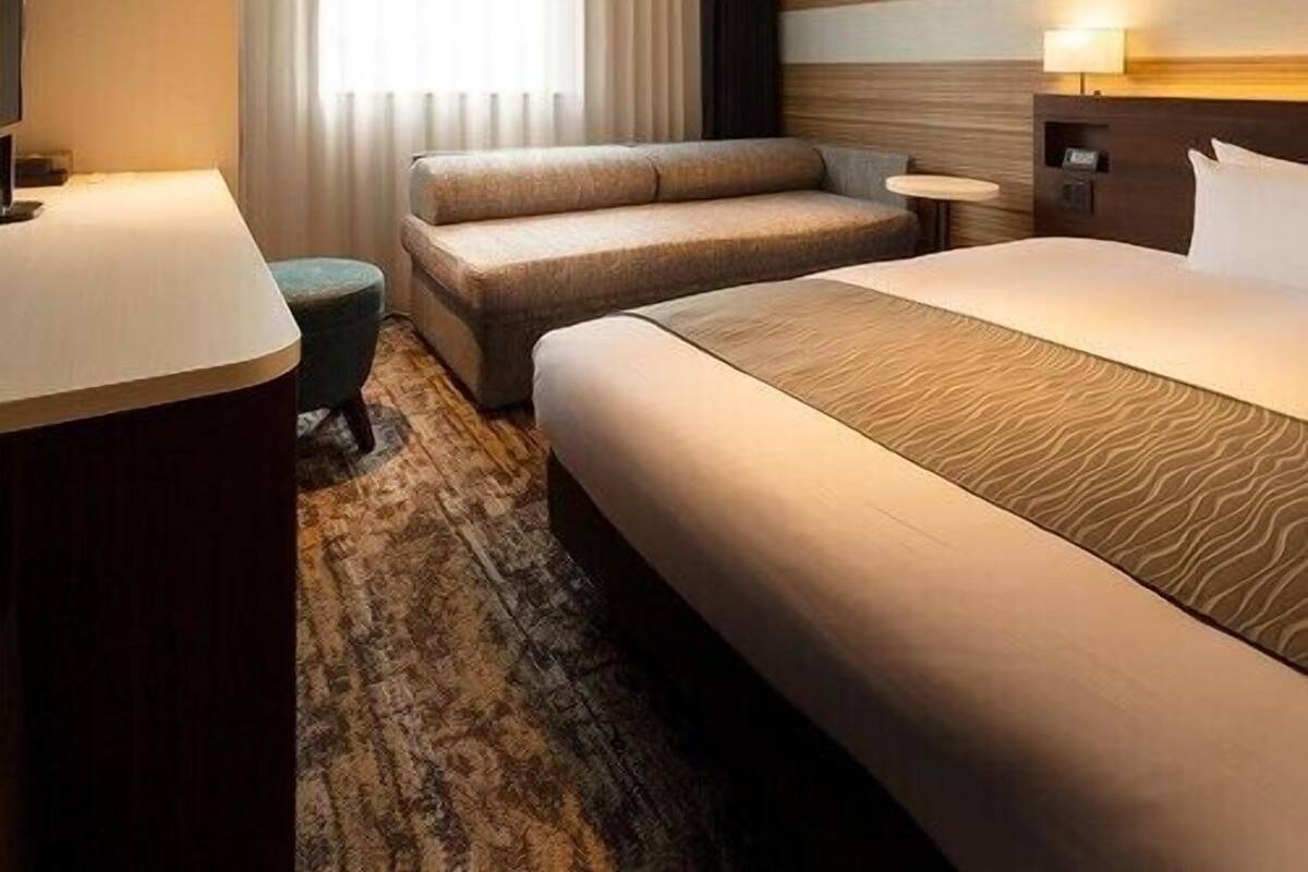 Una habitación de hotel con una cama grande, un sofá, una mesita y un escritorio.