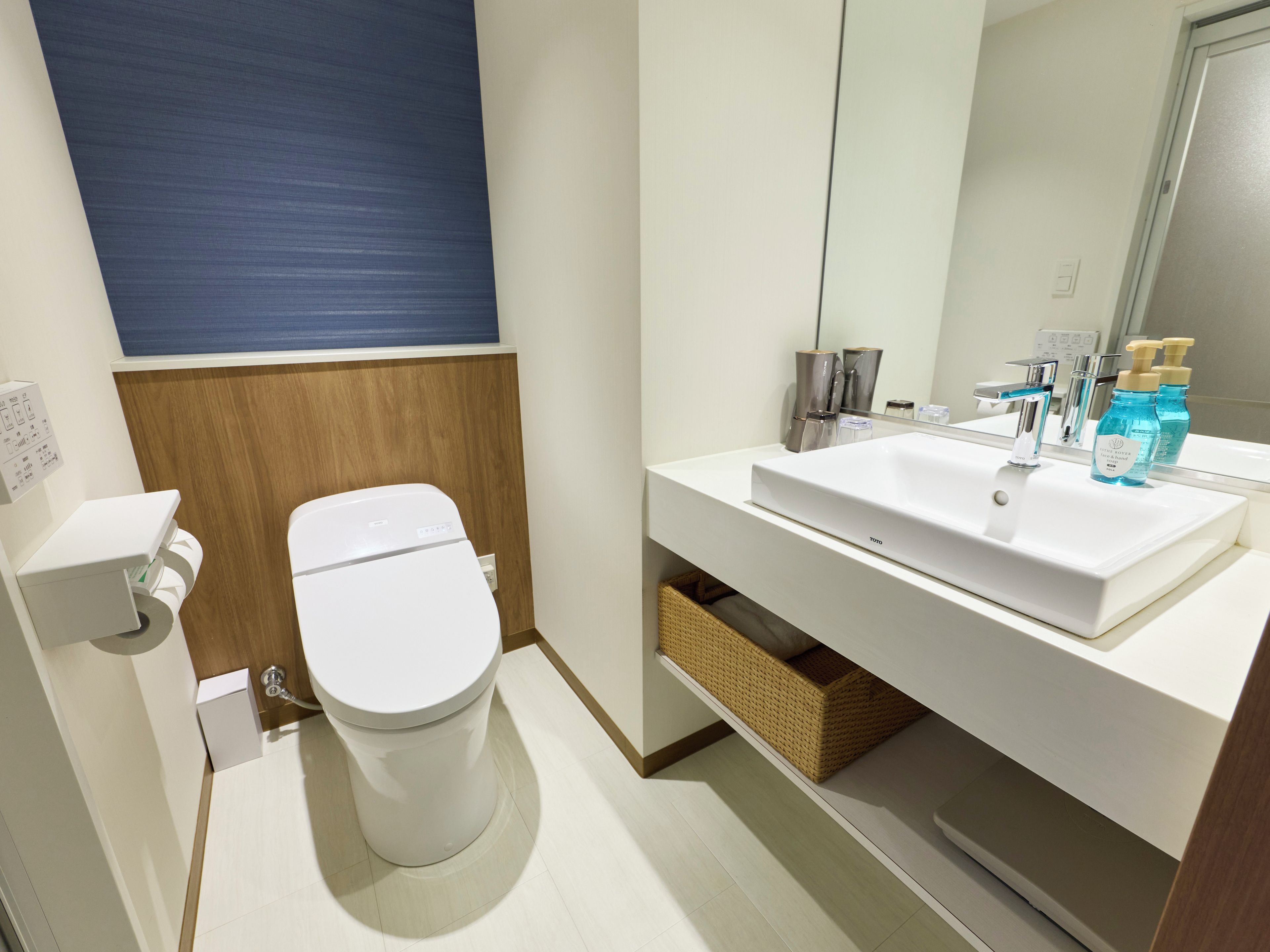 A modern bathroom with a white toilet, a white sink, and a mirror above the sink.