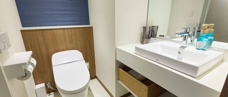 A modern bathroom with a white toilet, a white sink, and a mirror above the sink.