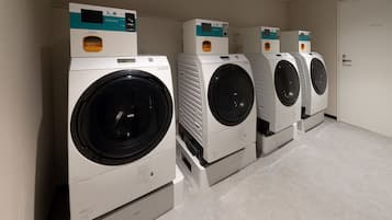 A row of four front-loading washing machines in a laundry room with a private door.
