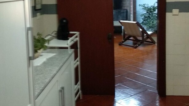 A kitchen with white cabinets, a sink, and a clock on the wall. - Villa Flor Campos (Cork Oak) (Vila Nova de Cerveira)