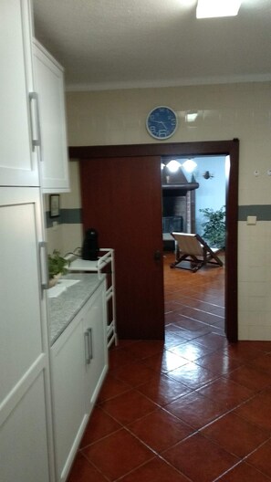 Une cuisine avec des armoires blanches, un évier et une horloge au mur.