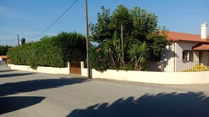 A quiet residential street with a white house, a gated entrance, and lush greenery. - Villa Flor Campos (Cork Oak) (Vila Nova de Cerveira)