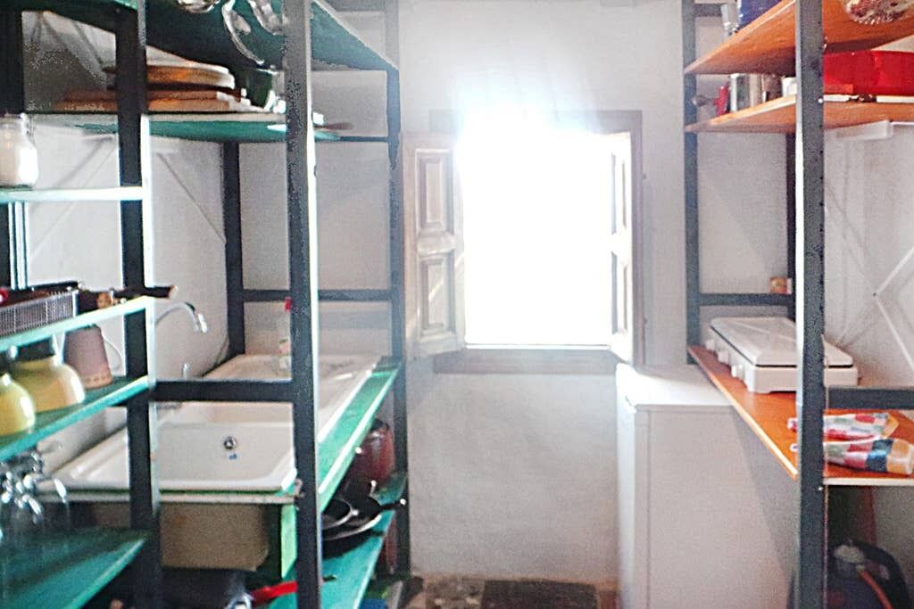A narrow hallway with shelves on either side, leading to a door with a window.