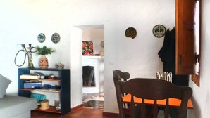 Un salon comprenant un canapé, une table à manger avec des chaises, une bibliothèque et un narguilé.