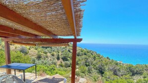 Un espace extérieur abrité, aménagé avec des sièges, et offrant une vue sur la mer.