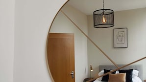 Ein Schlafzimmer mit einem Bett, einer Holztür, einer Pendelleuchte und einem gerahmten Bild an der Wand.