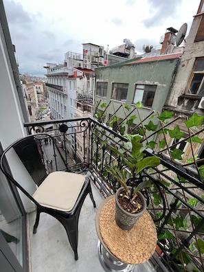 A balcony with a black chair, a potted plant, and a woven basket. - Royal Galata Hotel (Istanbul)