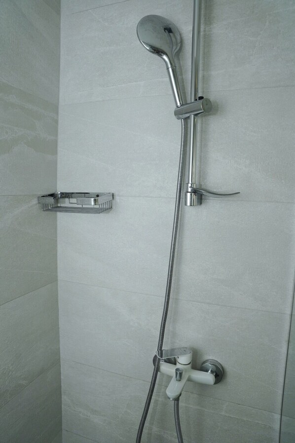 Une douche équipée d’un pommeau de douche à main, d’un flexible de douche et d’un robinet mural.