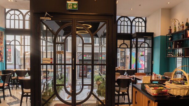 Ein Café-Interieur mit Glastür, Sitzbereich und einer Theke mit einem Korb.