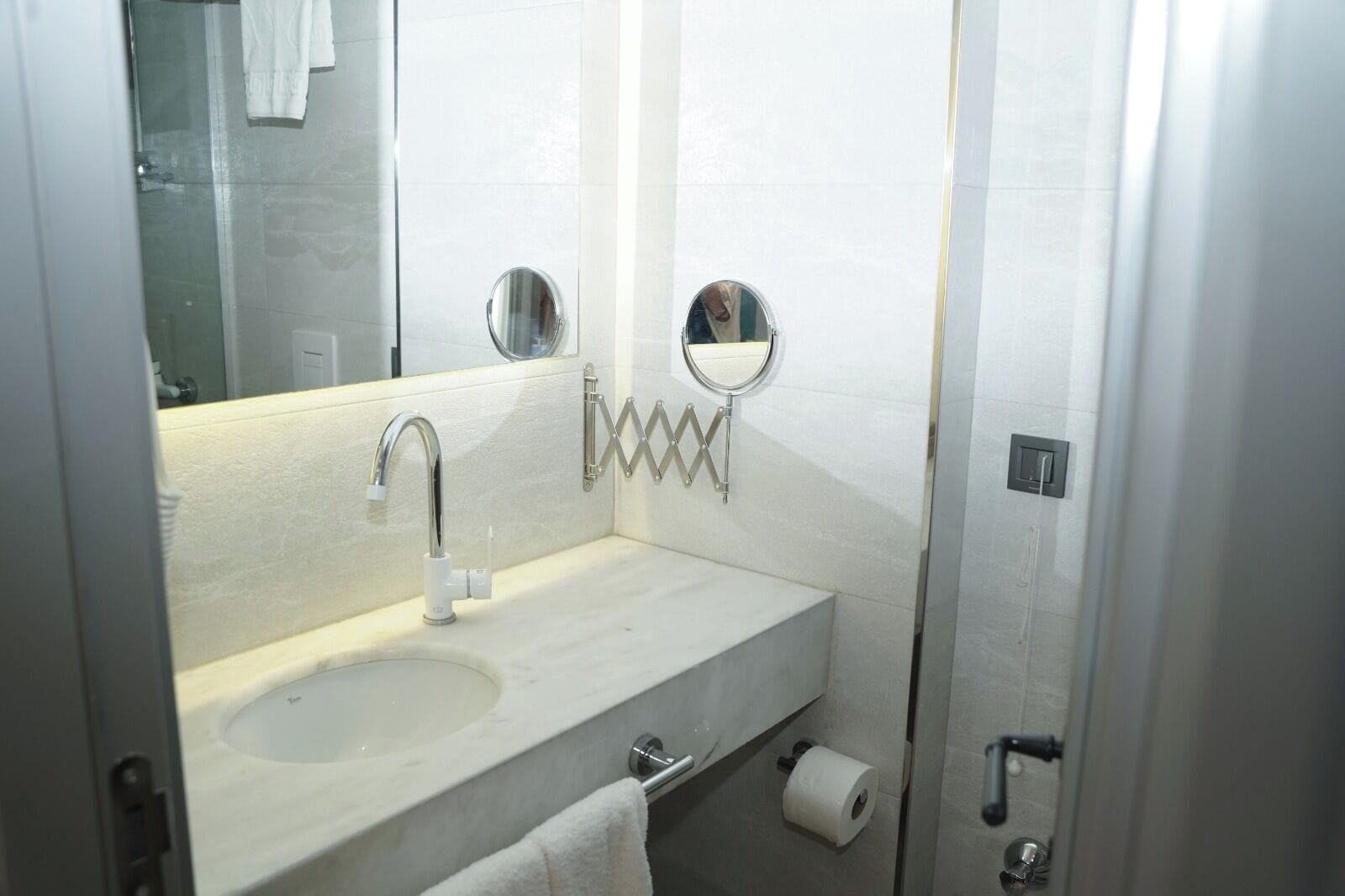 Une salle de bain équipée d’un lavabo, d’un miroir, d’un porte-serviettes et d’un rouleau de papier toilette.