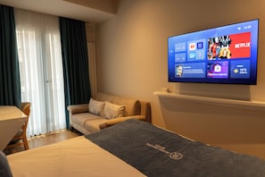 A hotel room with a bed, a sofa, a TV displaying a Netflix interface, and a window with curtains. - Royal Galata Hotel (Istanbul)