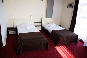 A hotel room with two single beds, a small table, and a nightstand. - GP Hotel (Barcanesti)