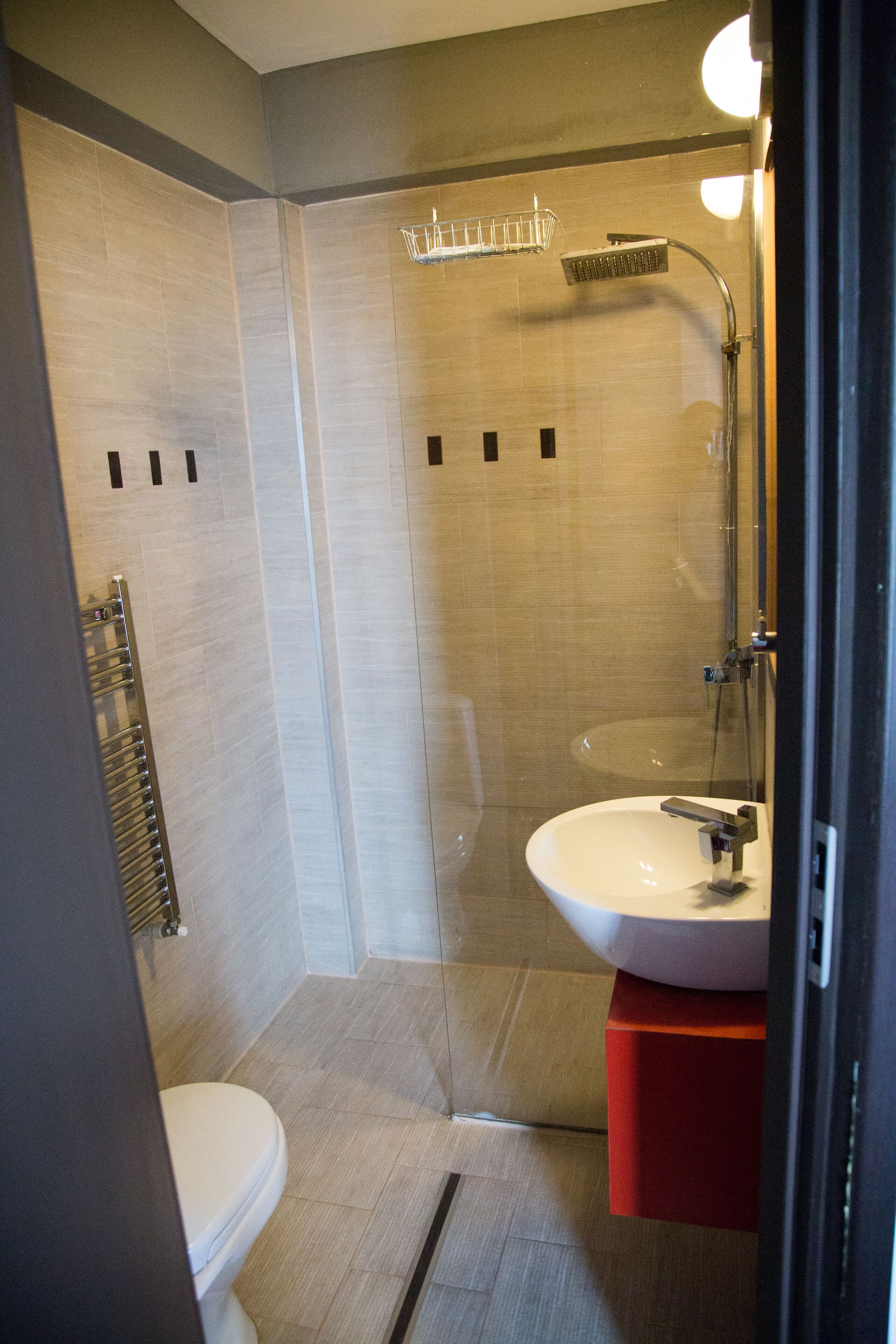 A modern bathroom with a glass-enclosed shower, a white sink, and a red cabinet.